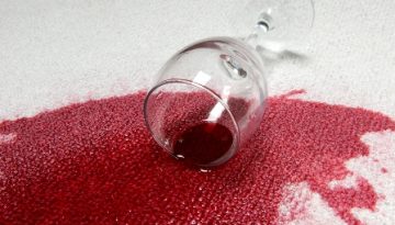A glass of red wine spilled on carpet.