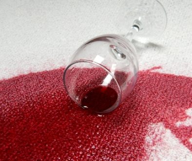 A glass of red wine spilled on carpet.